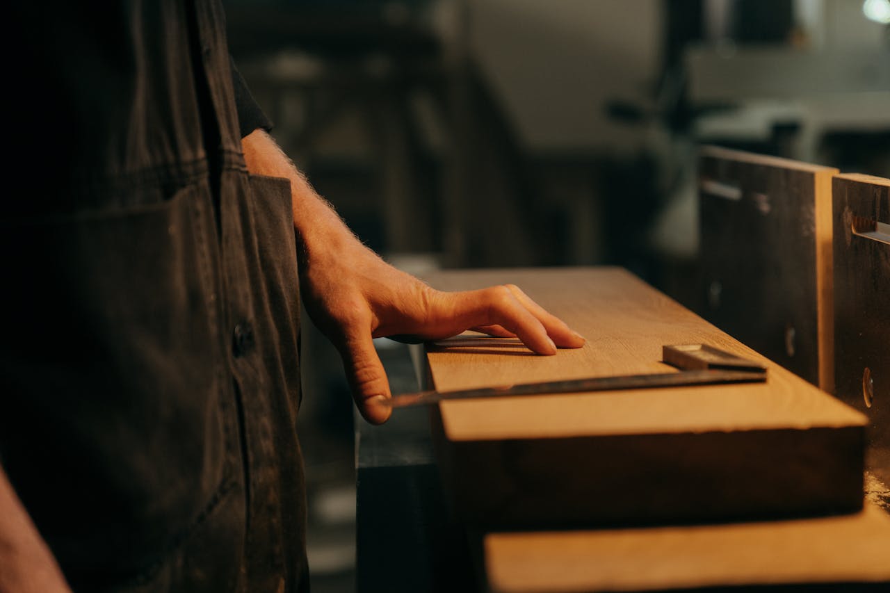 about-01 A craftsman measuring wood with precision tools in a workshop setting.